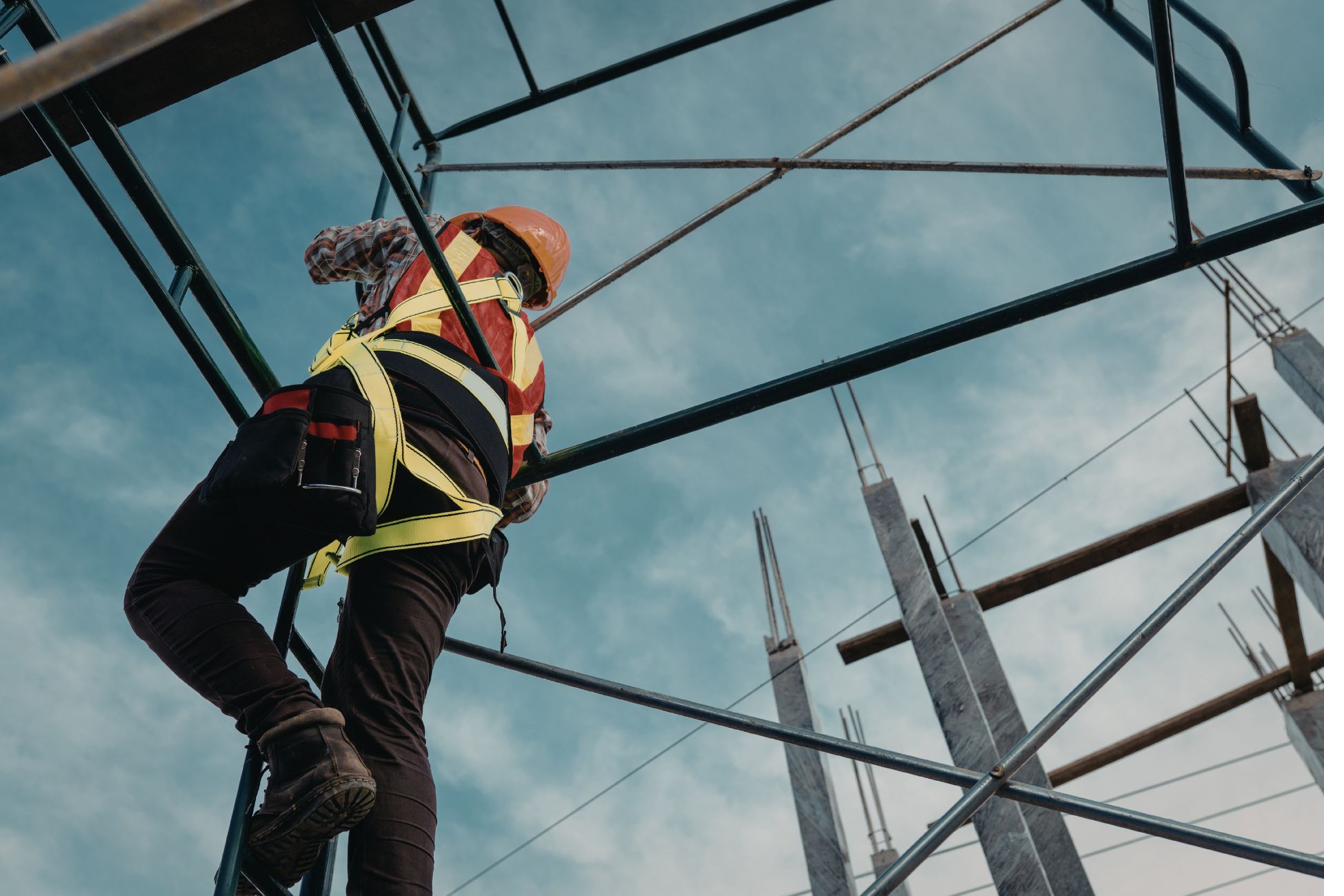 Construction worker climbing scaffolding in fall protection harness