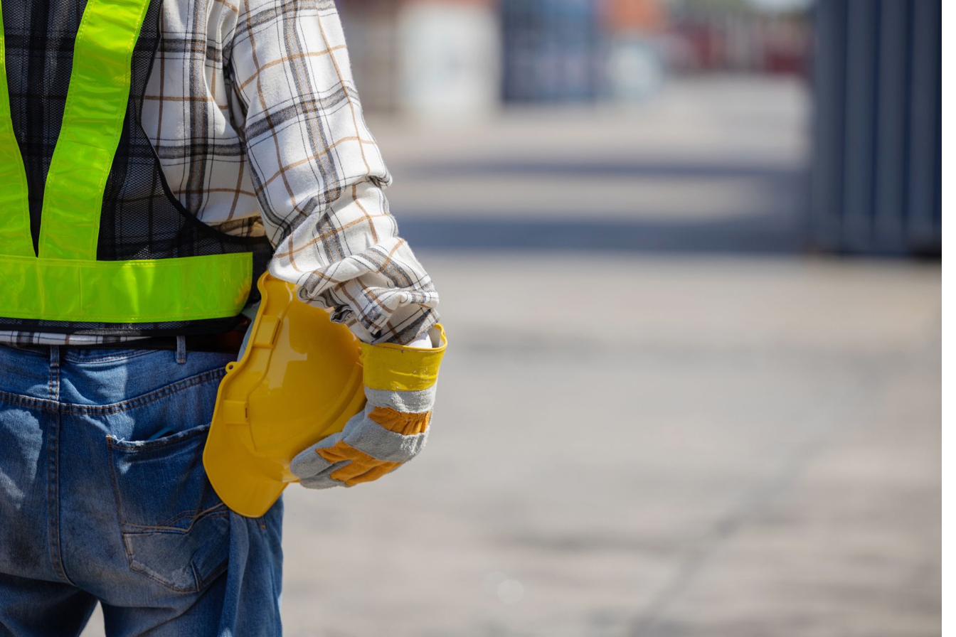 Construction worker holding hard hat with high-visibility vest